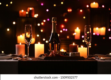 Romantic Dinner Table Setting With Burning Candles And Festive Lights