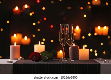 Romantic dinner table setting with burning candles and festive lights - Powered by Shutterstock