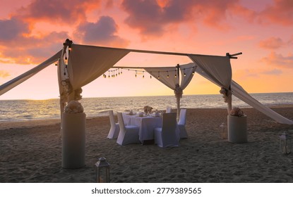 Romantic dinner table setting on the beach at sunset view scene with romantic dinner set up background