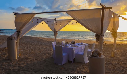 Romantic dinner table setting on the beach at sunset view scene with romantic scene of dinner set up background