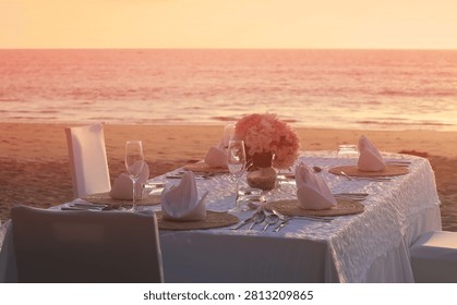 Romantic dinner table setting on the beach at sunset view scene with romantic scene of dinner set up background