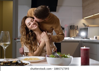 romantic dinner for two, married couple at the table with wine. A man kisses a woman on the neck. The concept of celebrating valentine's day, birthday,