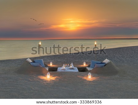 Romantic dinner with wine, candles and torches at ocean beach during wonderful sunset and flying birds couple. Honeymoon, proposal or wedding background concept.