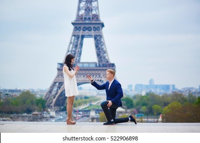 Romantic engagement in Paris, man proposing to his beautiful girlfriend near the Eiffel tower. Surprise proposal or elopement concept