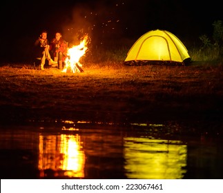 Romantic evening. A charming couple, camping, sitting around the campfire