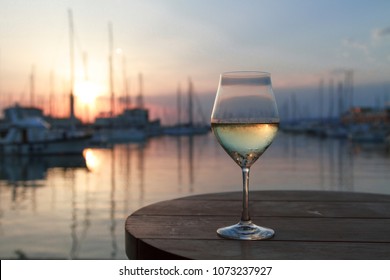 Romantic evening sunset with misty glass of white wine on background
sea and yacht club.