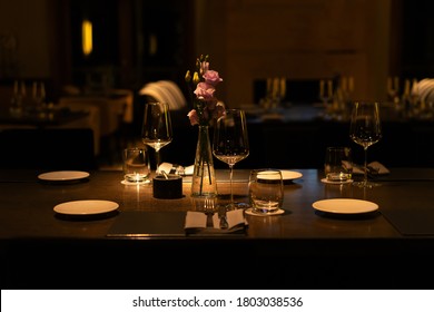Romantic Evening Table Setting With Wine Glasses And Flowers In Unrecognizeble Restaurant