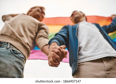 Romantic gay couple hugging, kissing and holding hands outdoors. Two handsome men holding LGBT pride flag. - Powered by Shutterstock