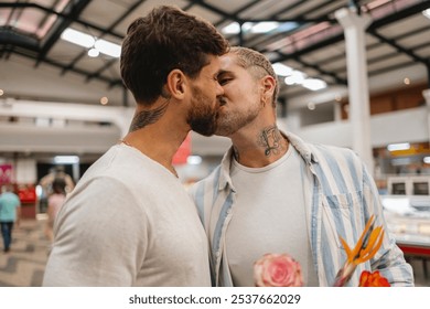 Romantic gay couple kissing while shopping for groceries in a supermarket, holding a bouquet of flowers, celebrating love and diversity - Powered by Shutterstock