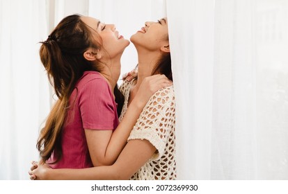 Romantic Gay Lesbians Holding Each Other Smiling. Beautiful Sensual Asian Homosexual Couple Intimate Moment Embracing In Bedroom By Window. Portrait Of Two Women Hugging With Affectionate Relationship