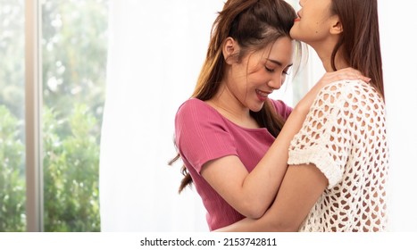 Romantic Gay Lesbians Holding Each Other Smiling. Beautiful Sensual Asian Homosexual Couple Intimate Moment Embracing In Bedroom By Window. Portrait Of Two Women Hugging With Affectionate Relationship