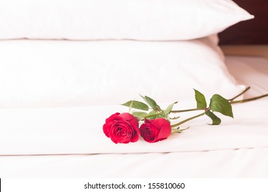 Romantic Getaway With Red Roses On Bed And Fluffy Pillows Background 