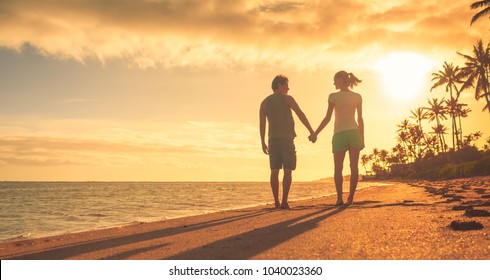 Romantic Getaway. Young Couple Holding Hands Walking Down The Beach. Love And Relationships Concept. 