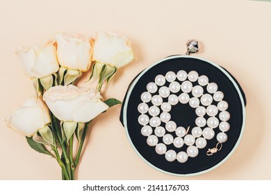 Romantic Gift Pearl Necklace Next To Bouquet Of Roses, Flat Lay Composition On Beige Background, Top View