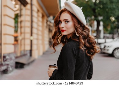 Romantic ginger woman in french beret looking back. Outdoor photo of adorable brunette girl enjoying autumn day.