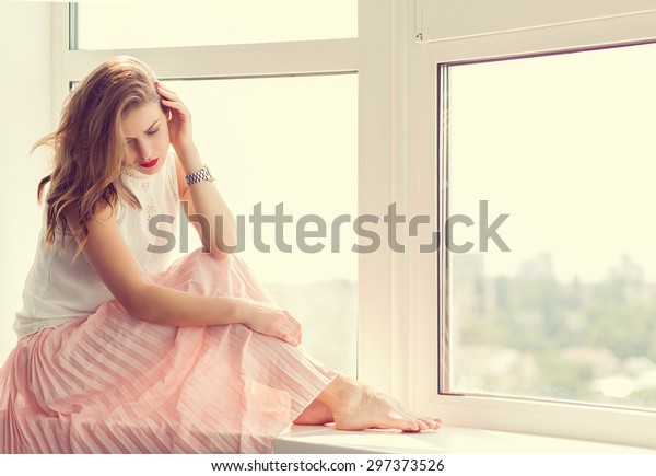 窓際に座る長いガウンを着たロマンチックな女の子 の写真素材 今すぐ編集