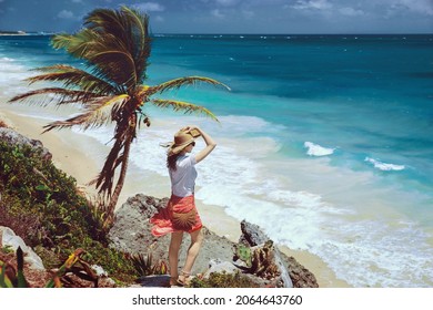 A romantic girl stands on a cliff overlooking the endless turquoise Caribbean Sea in Tulum. Paradise landscapes of Tulum on tropical coast and picturesque beach, ruins of Tulum, Mexico 