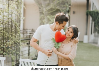 Romantic Happy Asian Couple In Love Having Fun With Heart Flower While Hugging. Vanlentine Day Concept.