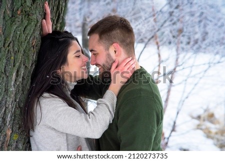 Romantic, happy couple walks in the park in winter. Man and woman hugging and kissing on valentines day. 