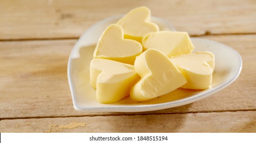 Romantic Heart Shaped Butter Pats On A Matching White Plate In A Close Up Low Angle View On Wood In A Food Styling Concept