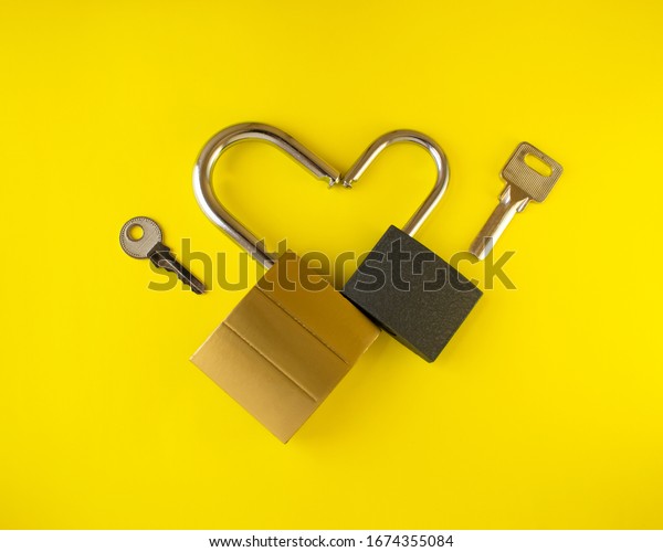 Romantic heart of two\
padlocks .Two metal locks and two keys as a symbol of love. On a\
yellow background.