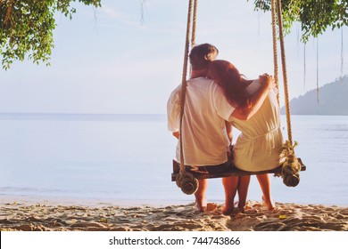 Romantic Holidays For Two, Affectionate Couple Sitting Together On The Beach On Swing, Silhouette Of Man Hugging Woman