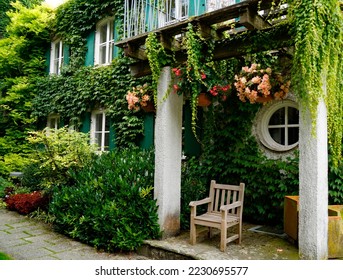 romantic house overgrown with ivy and flowers in the botanical garden on a sunny summer day in Augsburg, Bavaria, Germany                               