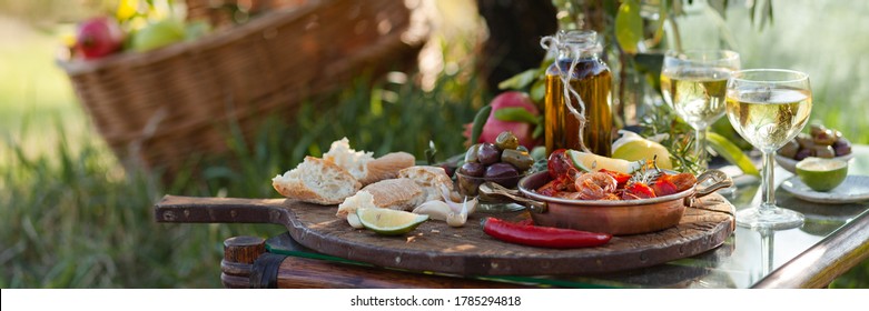 Romantic Italian Lunch Outside Of A Couple: Copper Pan With Delicious And Spicy Fried Shrimps With Herbs And Garlic, Bottle Of Olive Oil, Wine, Bread. Luxury Lifestyle, Gourmet Food. Banner