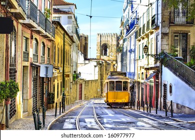 Romantic Lisbon street with the typical yellow tram and Lisbon Cathedral on the background 