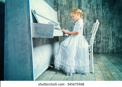 Romantic little girl in white dress playing the piano. Music and art concept. Retro style. 