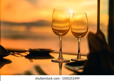 Romantic luxury dinner.Empty glasses and tropical sunset with sea background.Romantic evening with stunning sunset.