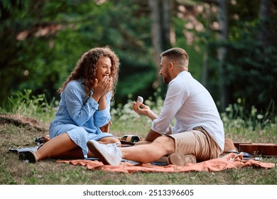 Romantic man with engagement ring proposing his girlfriend on a picnic.  - Powered by Shutterstock