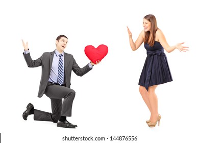 Romantic man giving a red heart to a young woman, isolated on white background
