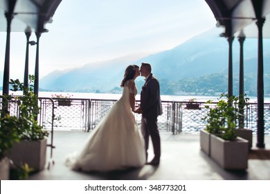 Romantic married couple kissing at port lake and mountains background