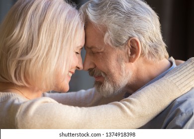 Romantic mature couple in love, wife and husband face to face, middle aged family enjoying tenderness and closeness, grey haired man and woman with closed eyes touching foreheads, close up