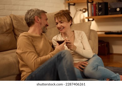 Romantic mature couple relaxing at home and drinking red wine - Shutterstock ID 2287406261