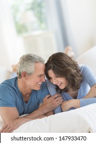 Romantic Mature Couple Smiling Together In Bed At Home