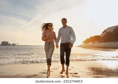 Romantic Middle Aged Couple Running Together On Beach At Sunset, Happy Mature Spouses Holding Hands And Smiling, Man And Woman Spending Time On Ocean Shore, Enjoying Outdoor Date, Copy Space - Powered by Shutterstock