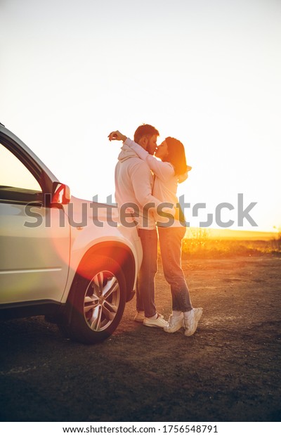 romantic moment couple kissing on sunset near white\
suv car