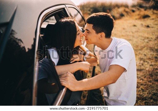 romantic moment couple kissing  on ksunset near black\
suv car