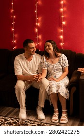 A romantic moment shared between a man and woman, illuminated by warm string lights, creating an intimate atmosphere at home