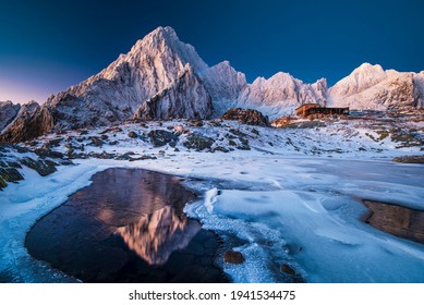 Romantic mountain hut in a snowy valley in the middle of the mountains with majestic mountains reflected on the lake surface. Lake with ice structures. High Tatras, Vysoke Tatry, Slovakia - Shutterstock ID 1941534475