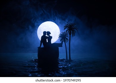 Romantic night scene. Fantasy night landscape with little island with palms and full moon over sea. Creative table decoration. Silhouette of romantic couple on uninhabited island. Selective focus.