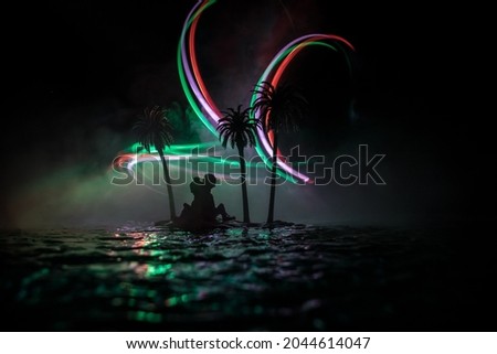 Romantic night scene. Fantasy night landscape with little island with palms and romantic couple silhouettes. Creative table decoration. Fantasy tropical beach. Selective focus.