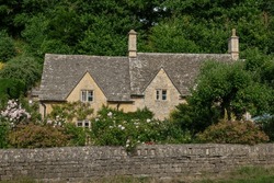 Romantic Old Stone Cottage In Iconic Bibury Village On A Sunny Summer Day. A Picturesque House Peeks Through A Lush Garden. Charming Tourist Destination In The British Countryside Worth Visiting.