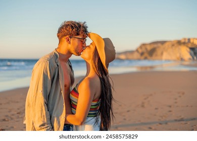 A romantic and passionate moment captured as a multicultural hispanic couple kiss deeply on the beach during a beautiful summer sunset, with the sea in the background - Powered by Shutterstock