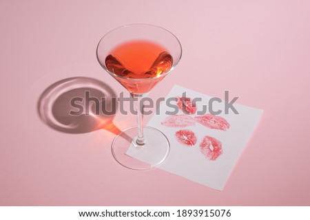 Romantic pastel pink composition made of cocktail glass and paper with lipstick kisses. Trendy, Valentine's Day concept.