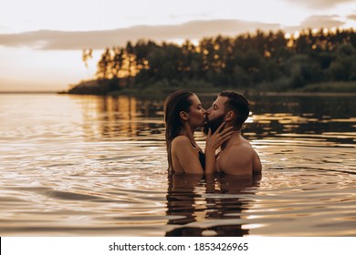 Romantic Photo Session In The Water. A Guy And A Girl Swim In The Lake In The Evening. Beautiful Sunset.