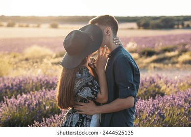 A romantic photograph of a young couple about to kiss in a lavender field at sunset. - Powered by Shutterstock