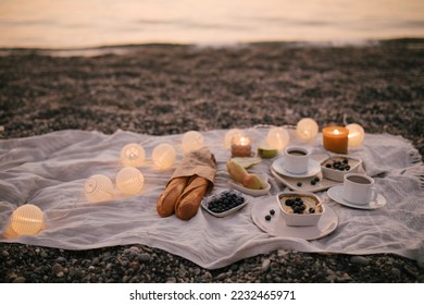 Romantic picnic by the sea at sunset decorated with garland. - Powered by Shutterstock